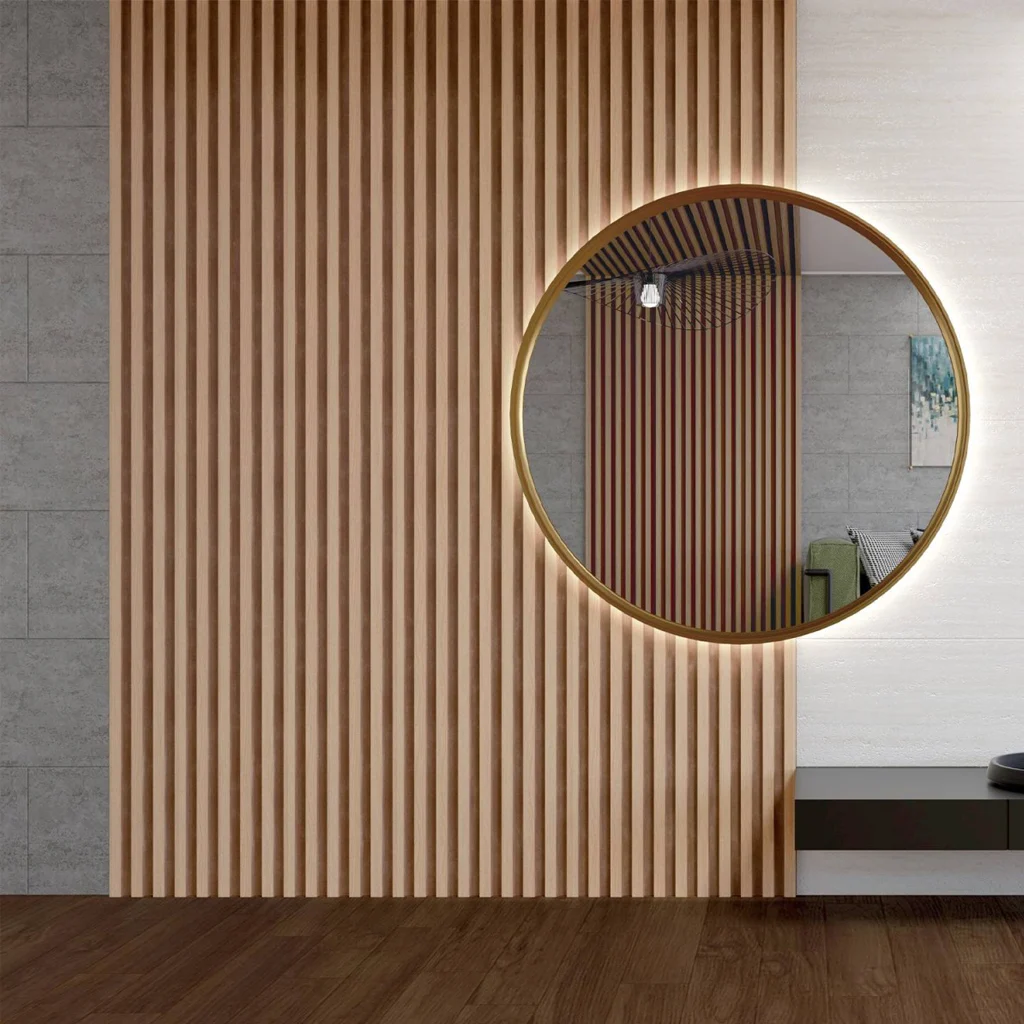 A modern interior with a large round mirror on a wall featuring vertical wooden slats. The mirror has a gold rim and reflects part of the room, including decor and furniture. The floor is dark wood.