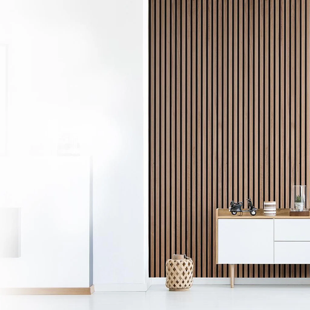 Minimalist interior with a white cupboard in front of a wall with vertical wooden slats, small decorative items on the cupboard, and a woven basket on the floor. The left side fades into a white background.